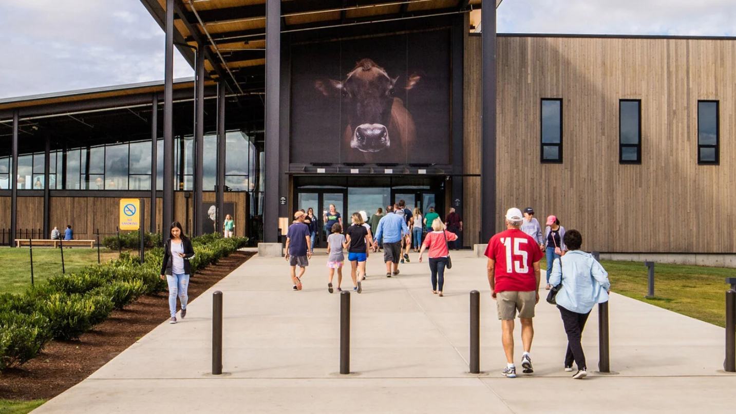 People walk in and out of large building emblazoned with a cow.