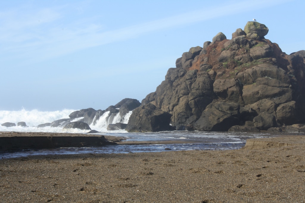 At the cliff-rimmed beach, a lazy creek flows into the sea, cutting through an enchanting scenic ocean cove.