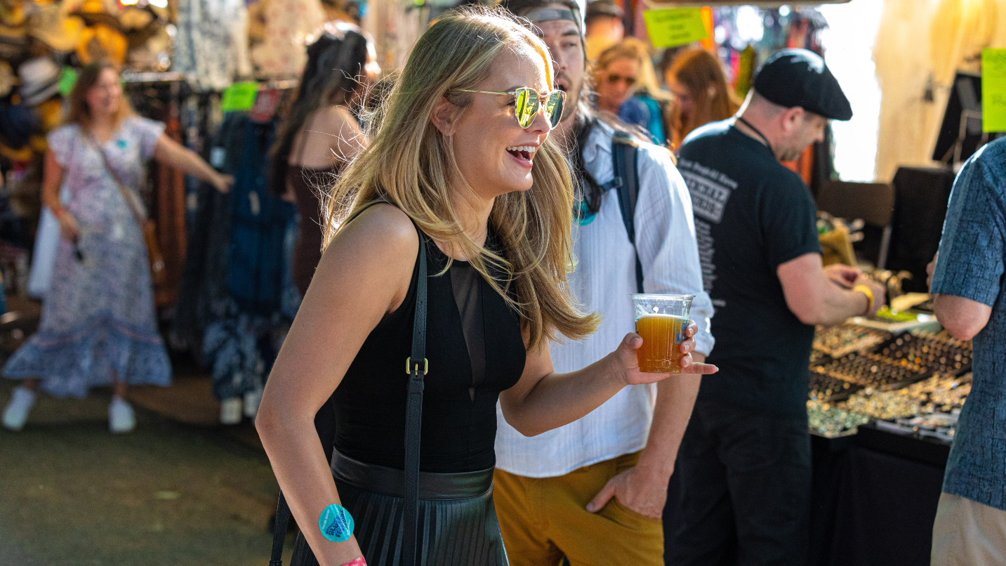 woman wears sunglasses and holds plastic cup of beer