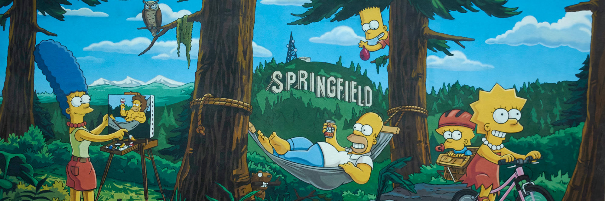 Mural of the Simpsons' cartoon family with a Springfield sign on the hill