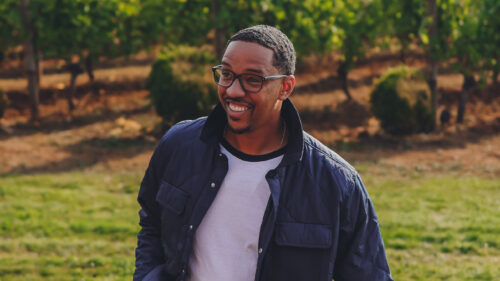 A candid portrait of a man smiling in a vineyard.