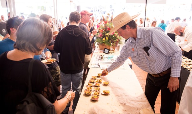 Cowboy-hat-wearing guest reaching for plate at Feast Portland