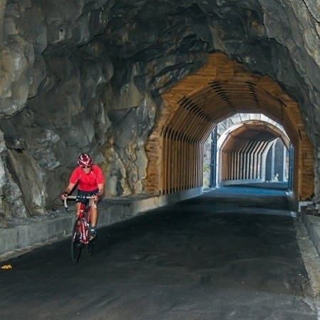 A lone cyclist riding through a stone tunnel