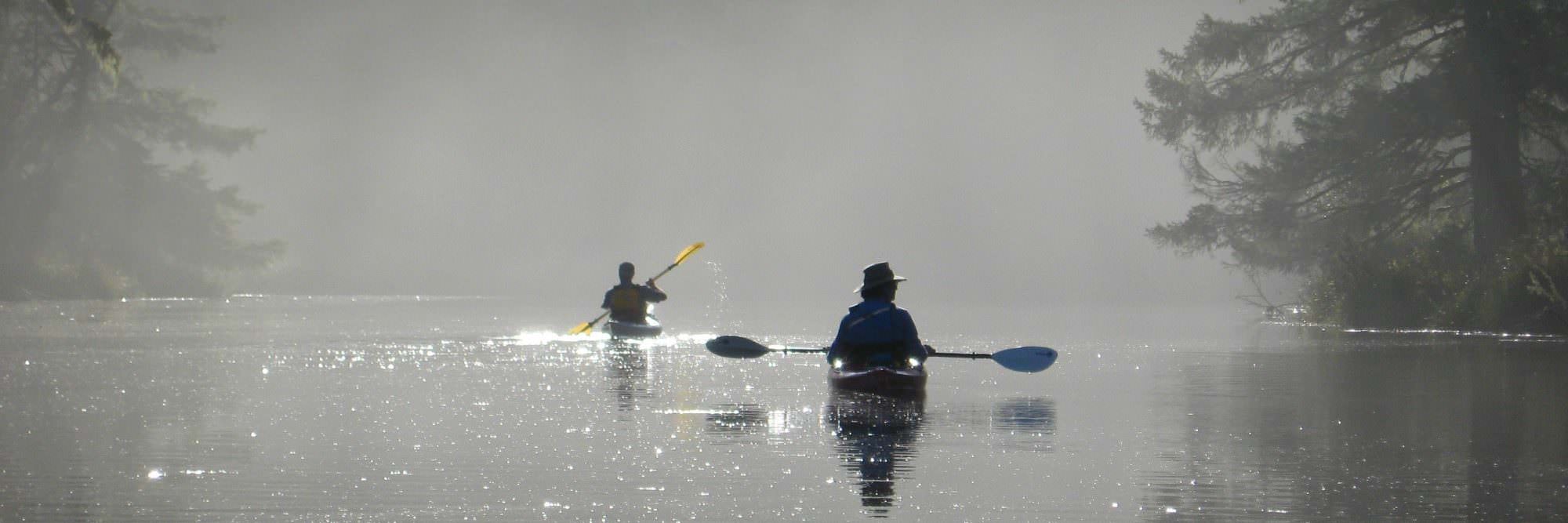 Kayakers rest on a foggy river