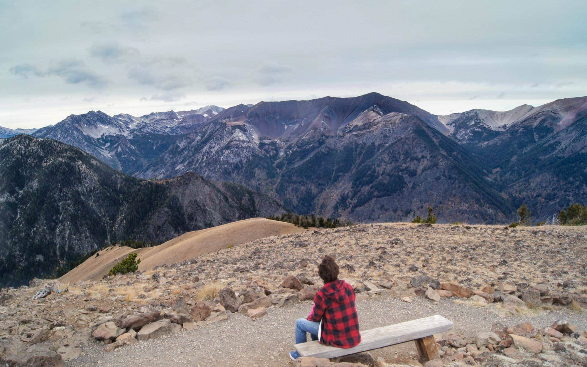 Man sitting on bench at top of Mt. Howard looking at the Wallowas
