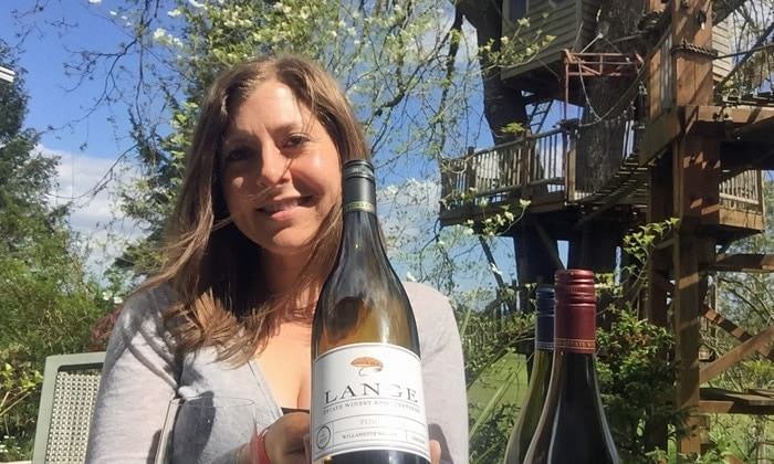 Girl with wine bottles in front of treehouse
