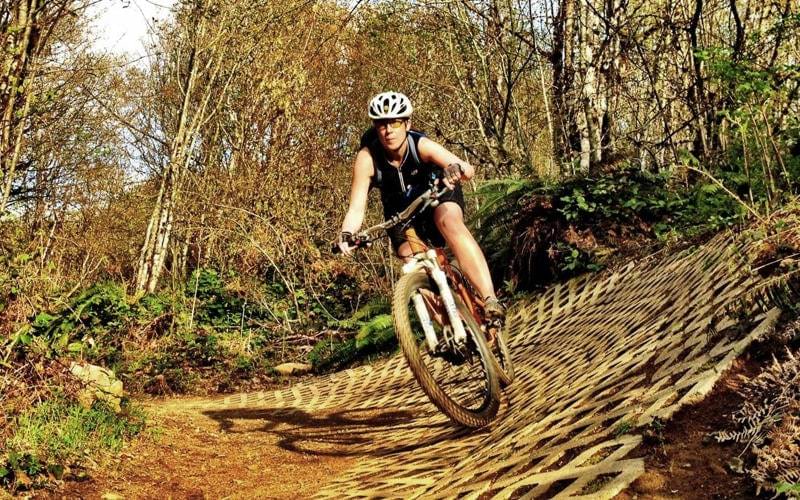 Female mountain biker pedals on slant.