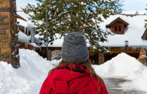 Girl in red coat looks at snowy entrance to The Village at Sunriver in Central Oregon.