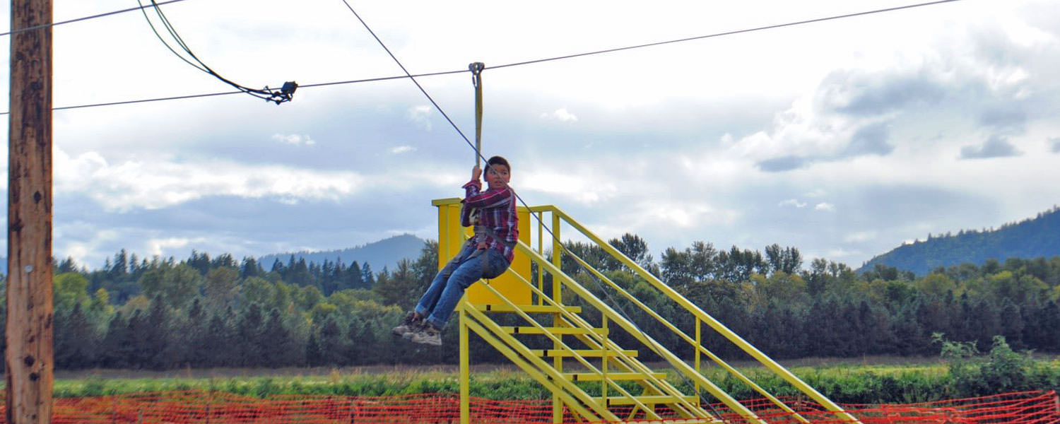 A young boy looks forward as he heads down a zip line.