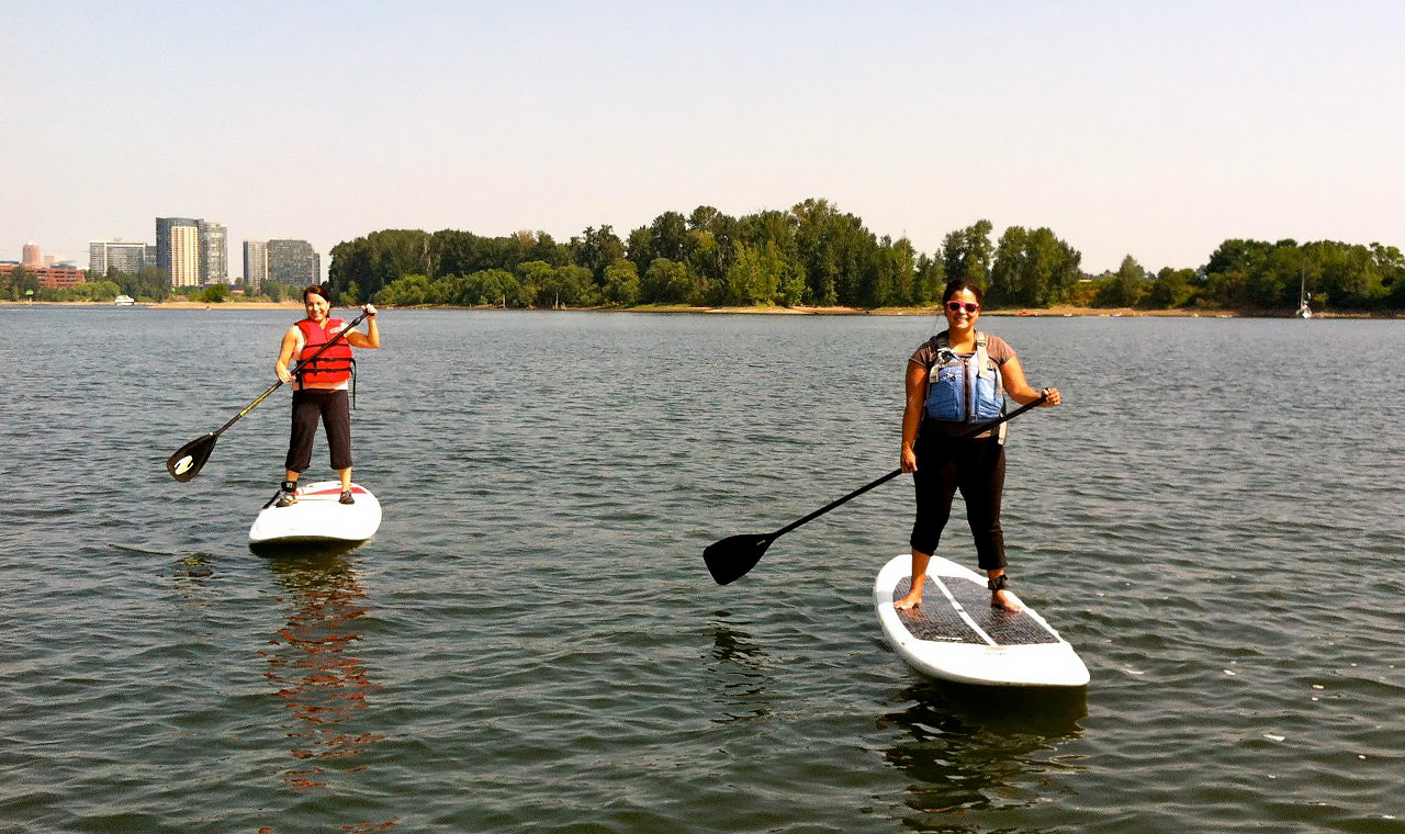 Two people stand on paddleboards