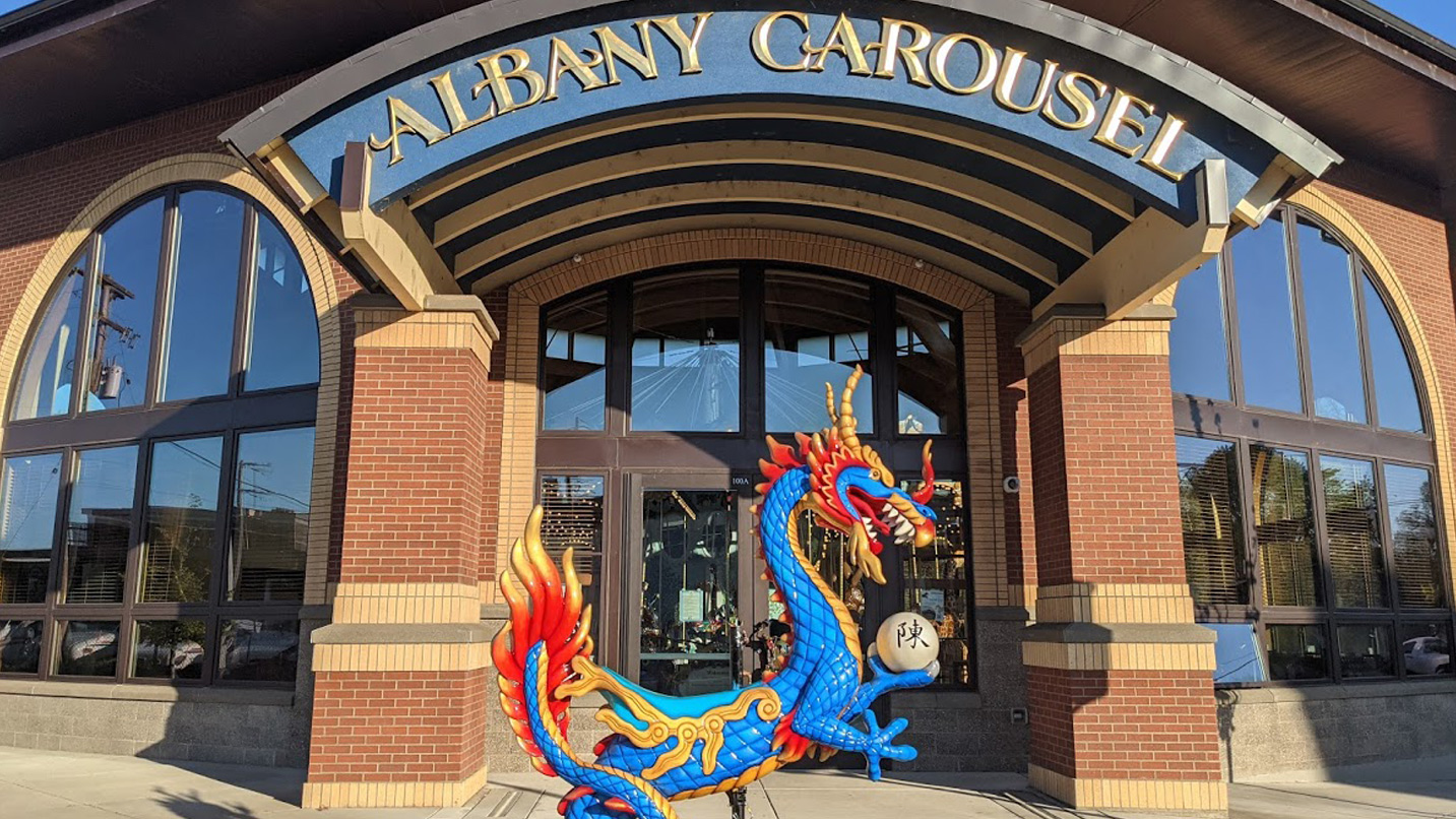 A brightly painted dragon sits in front of the entrance to the carousel