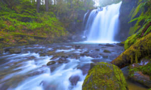 A long exposure photo of a waterfall shows white cascades and mossy rocks.