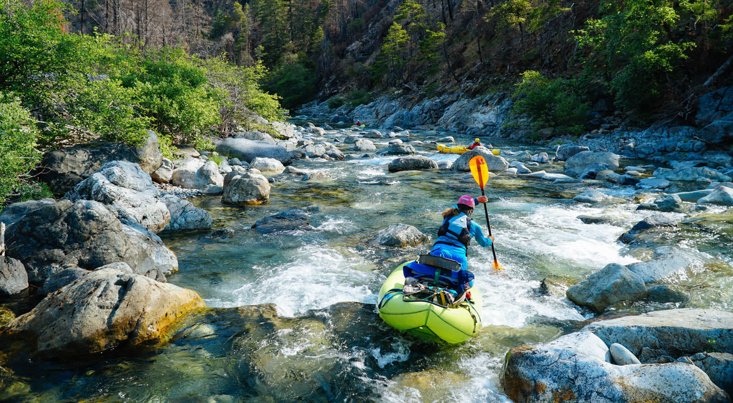 A rafter leans and paddles quickly down a rocky section of the river.