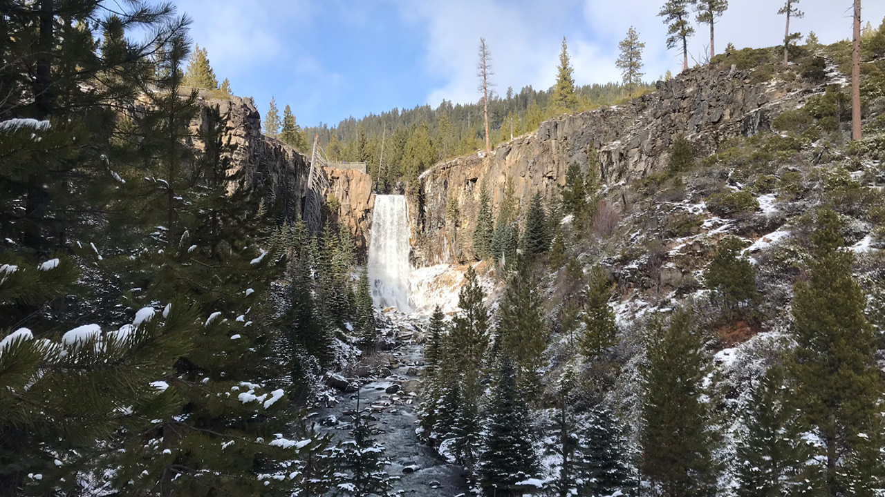 The woodsy landscape around Tumalo Falls is sprinkled with snow during the wintertime.