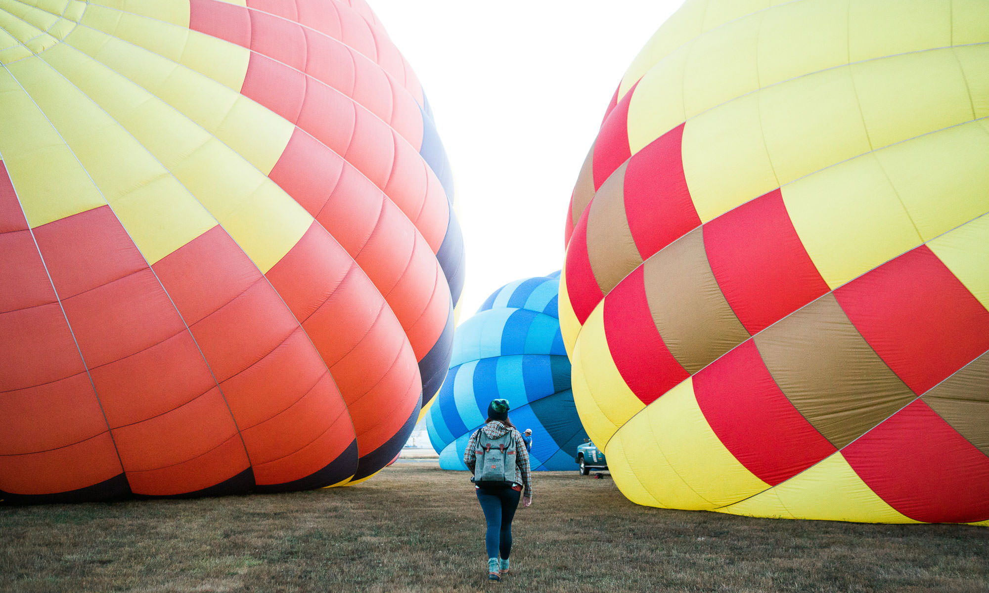 A girl walks between two deflated hot air balloons.