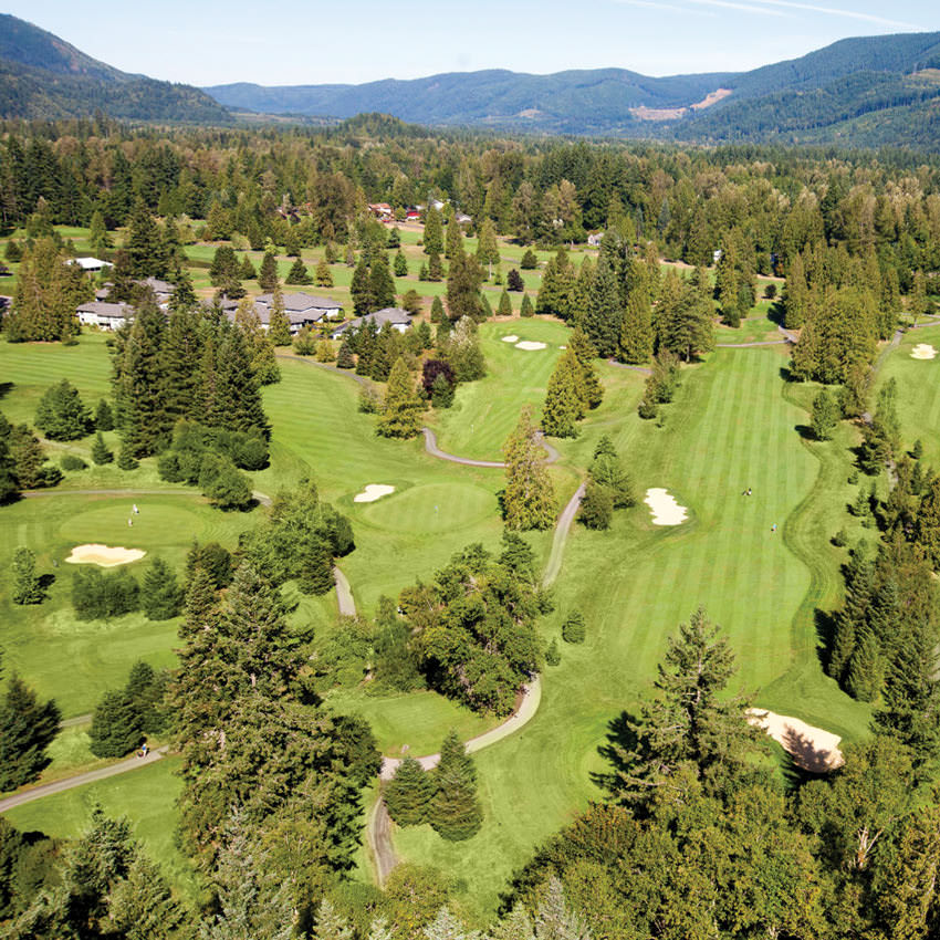 An aerial view of a lush golf course will hills in the distance