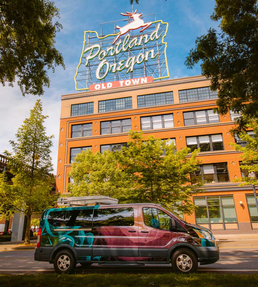An Escape Campervan sits below the iconic Portland, Oregon White Stag sign.