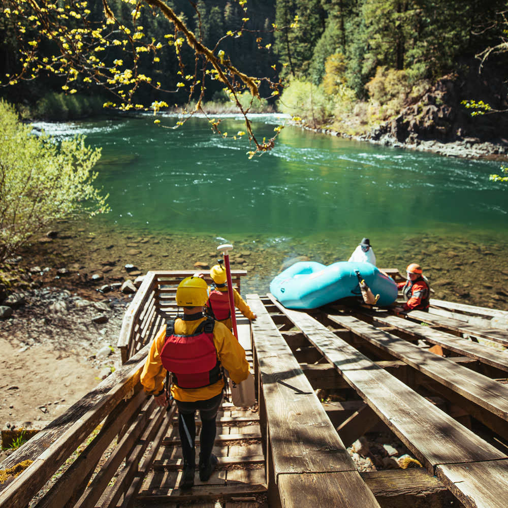 A group gets ready to raft a river that is turquoise blue.