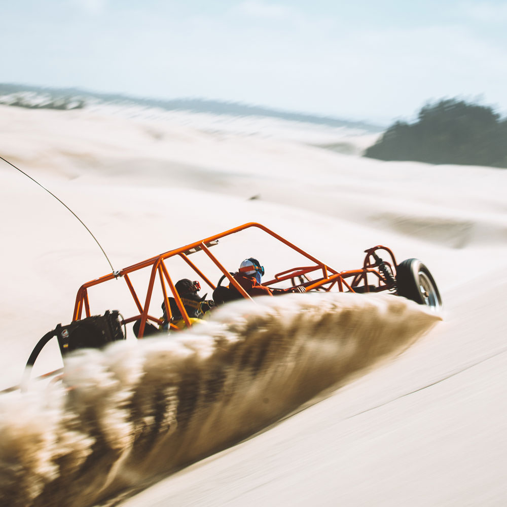 A dune buggy skids in the sand.