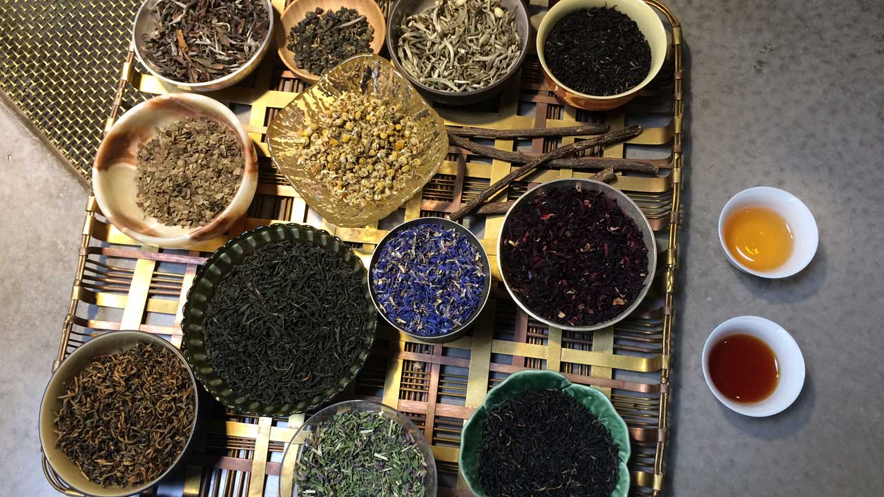 Different loose-leaf teas are displayed in bowls.