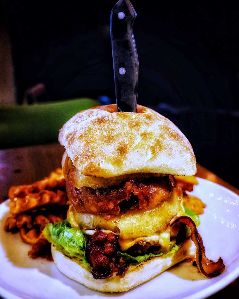A knife sticks out of a hearty burger at Brix Grill.