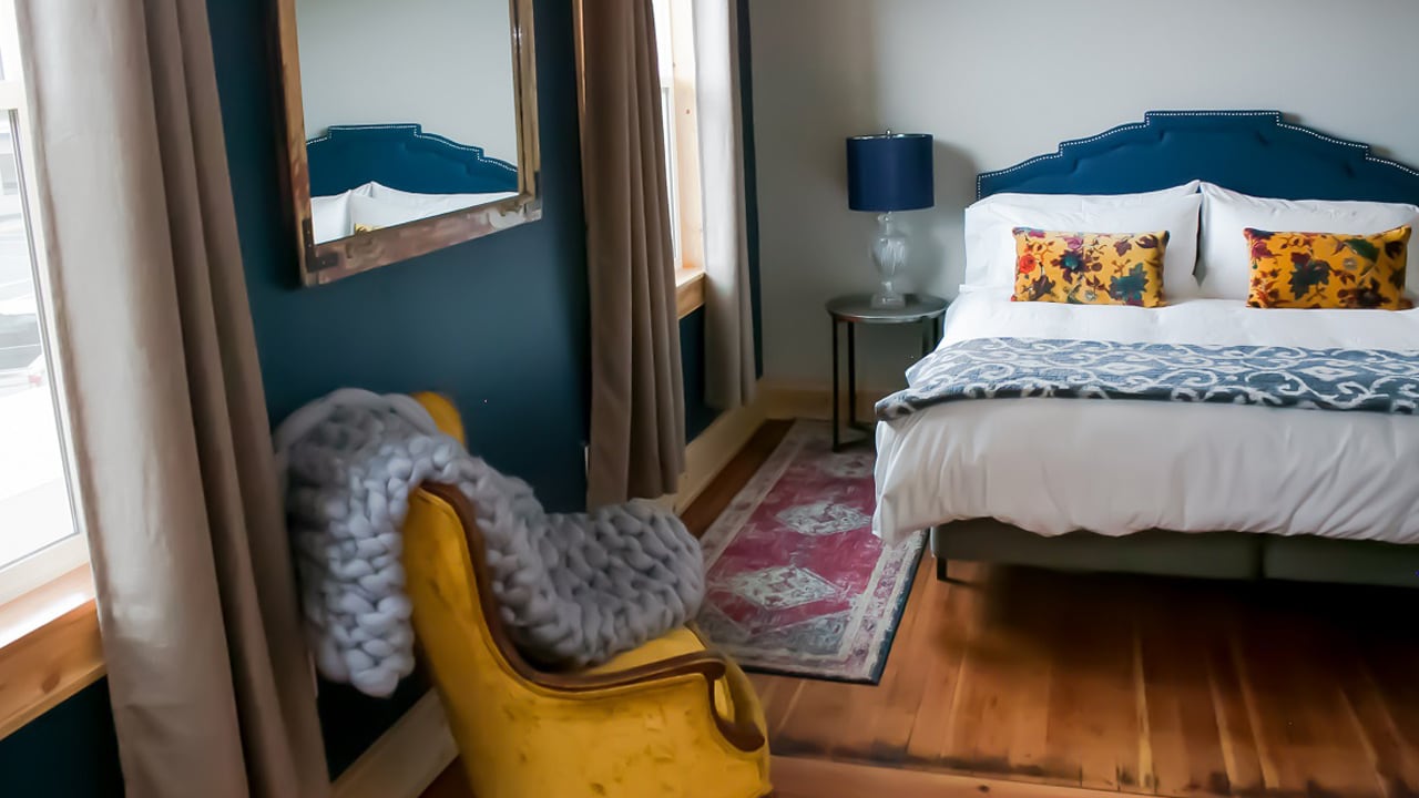 A hotel room features blue and yellow accents and hardwood floors.