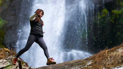 Hiker walks in front of waterfall