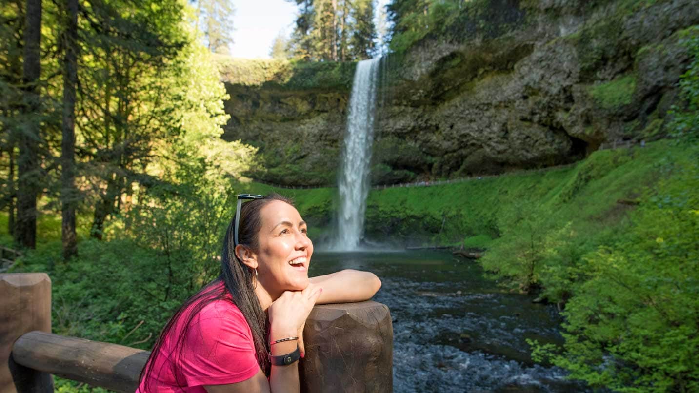 A woman stands in awe of a waterfall.