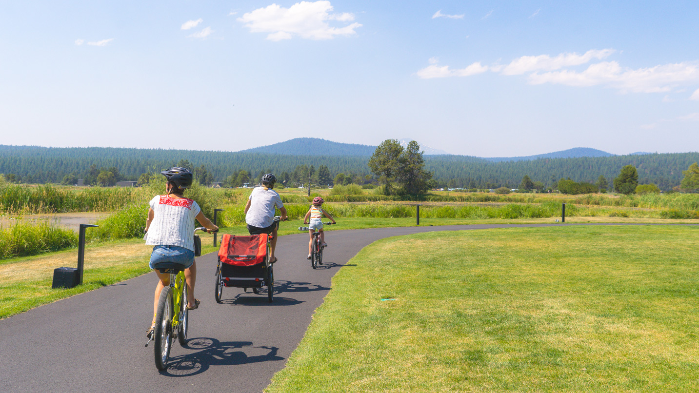 A family rides bikes on a paved path.