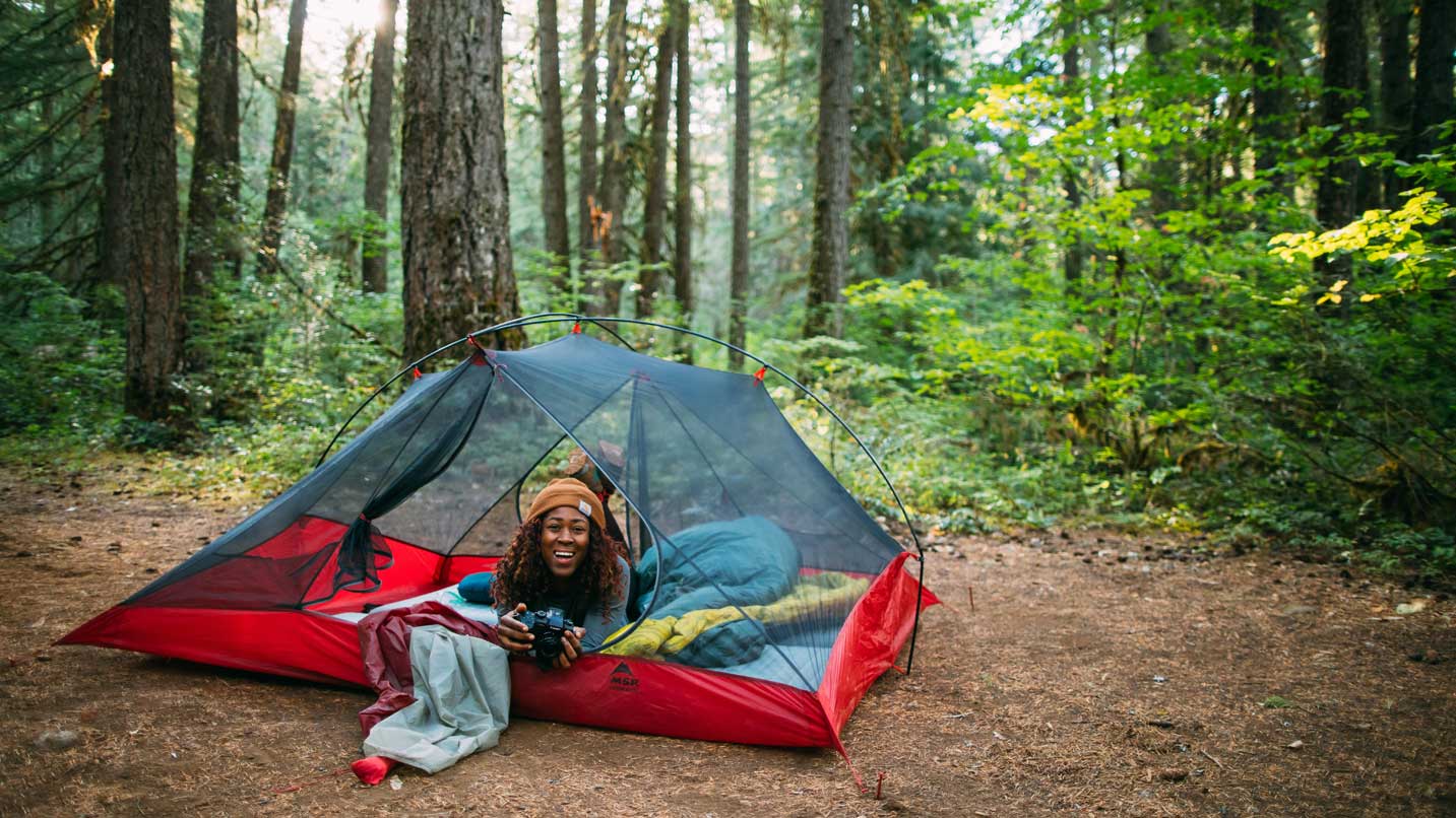 Analise leans out of her one-person tent to smile.
