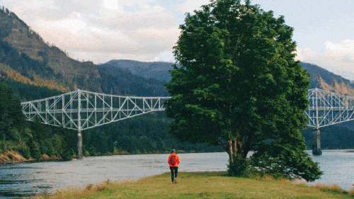 A girl stands on Thunder Island looking at the Bridge of the Gods.
