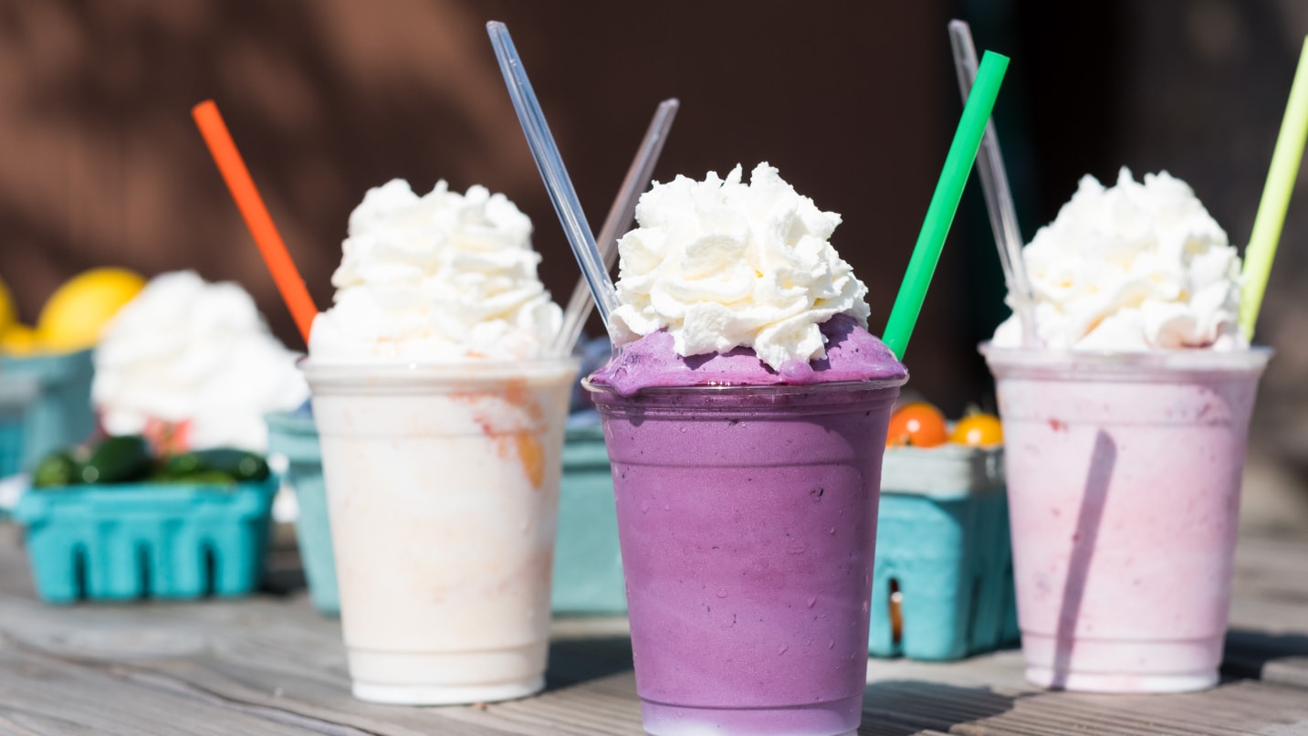 purple, pink and white milkshakes with whipped cream and straws