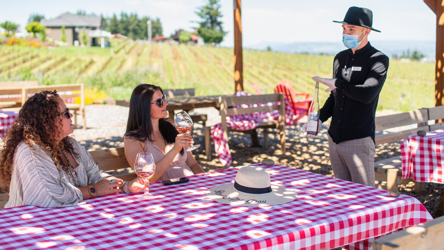 A masked waiter helps customers at a winery in Oregon.