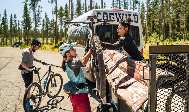 Two people placing bike on van