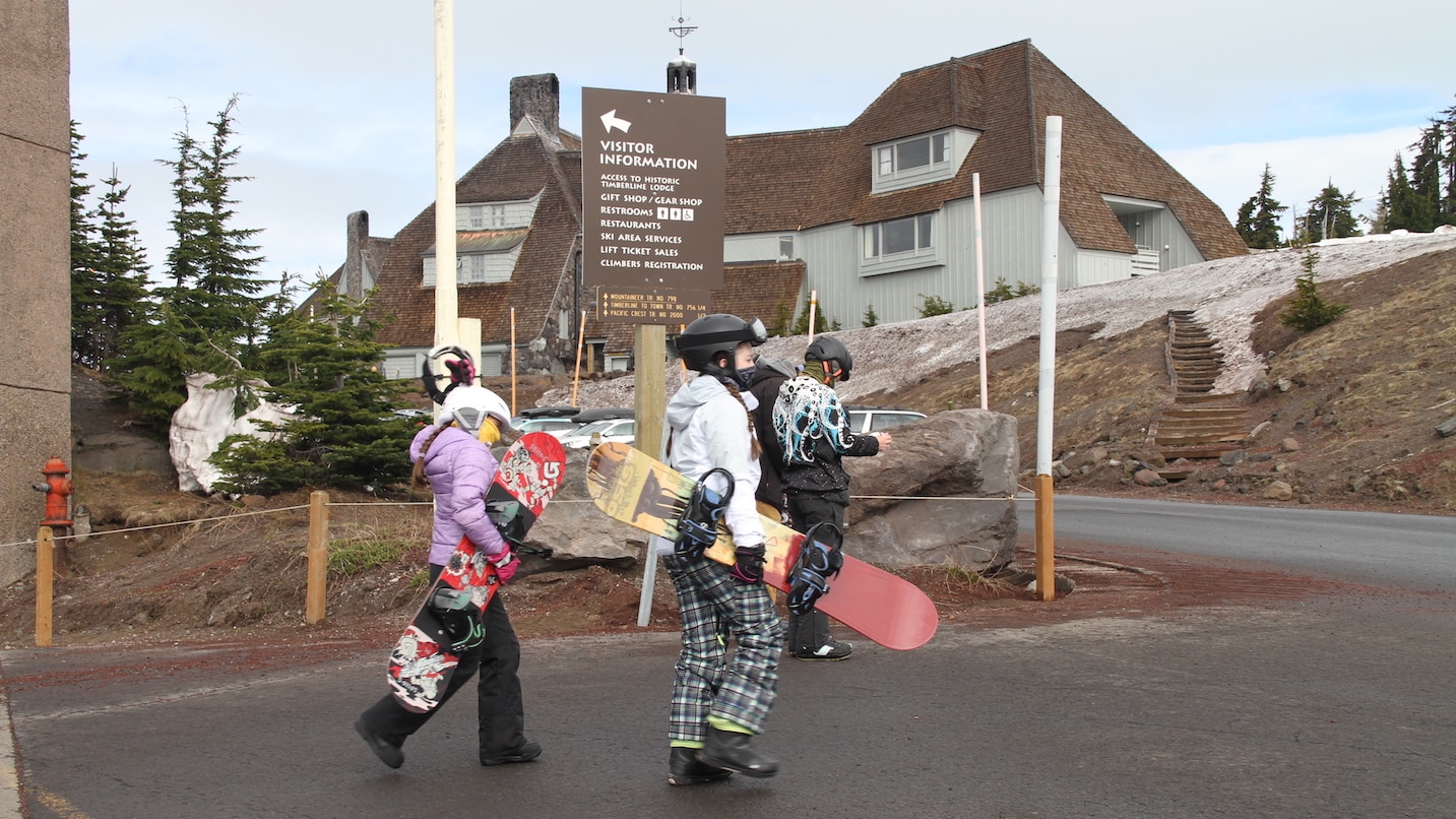 Young snowboarders wear face coverings as they walk to the lift.