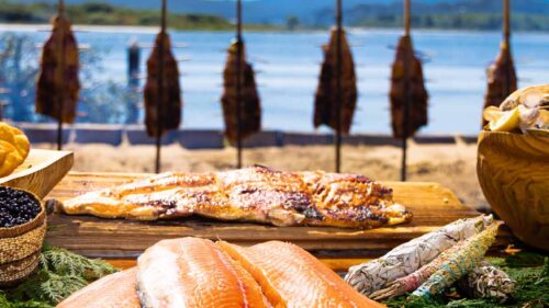 A spread of traditional first foods by the bay, including salmon, clams, camas, and huckeberries.