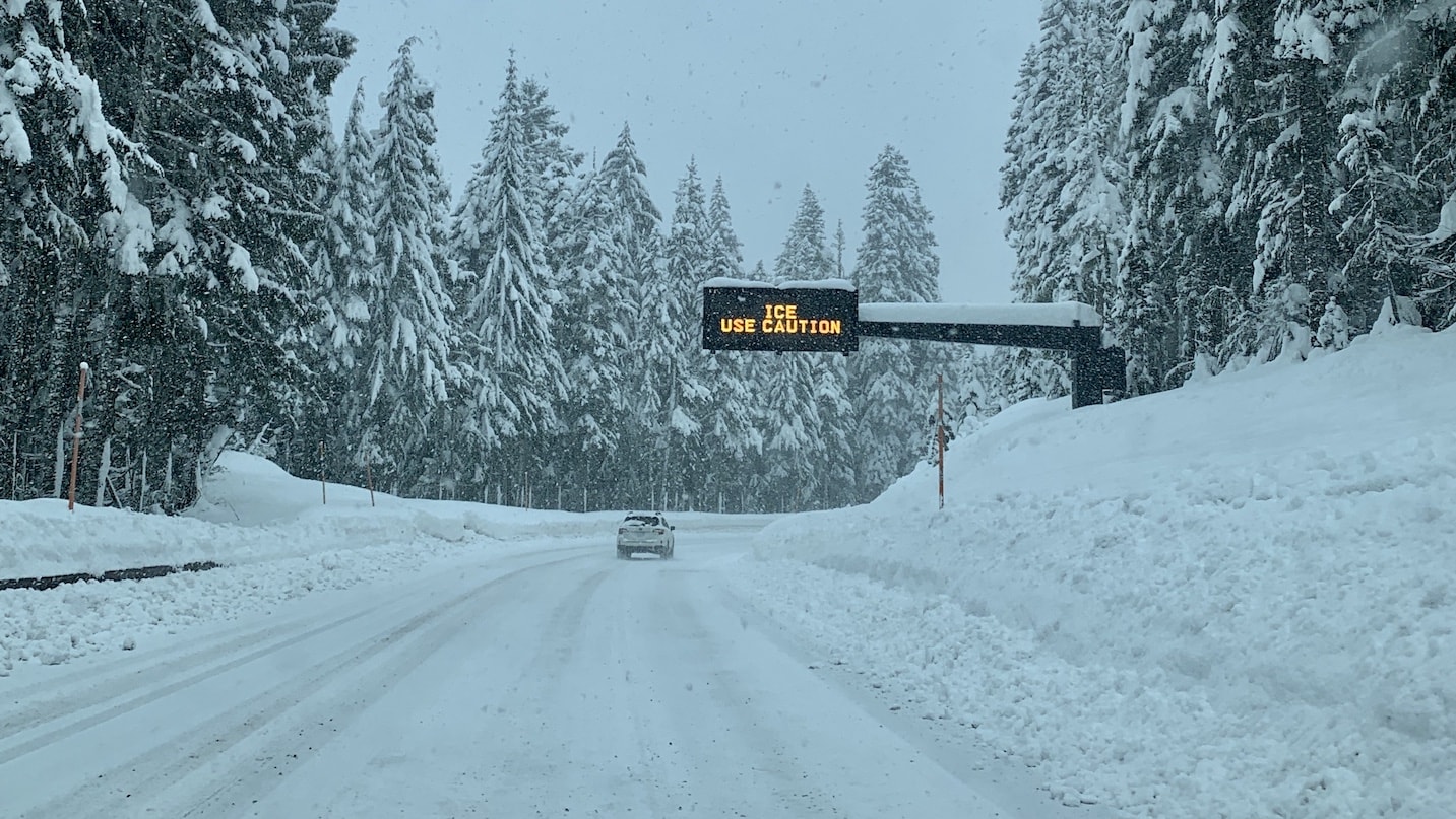 An electronic sign reads "Ice: Use Caution" above a snowy road.
