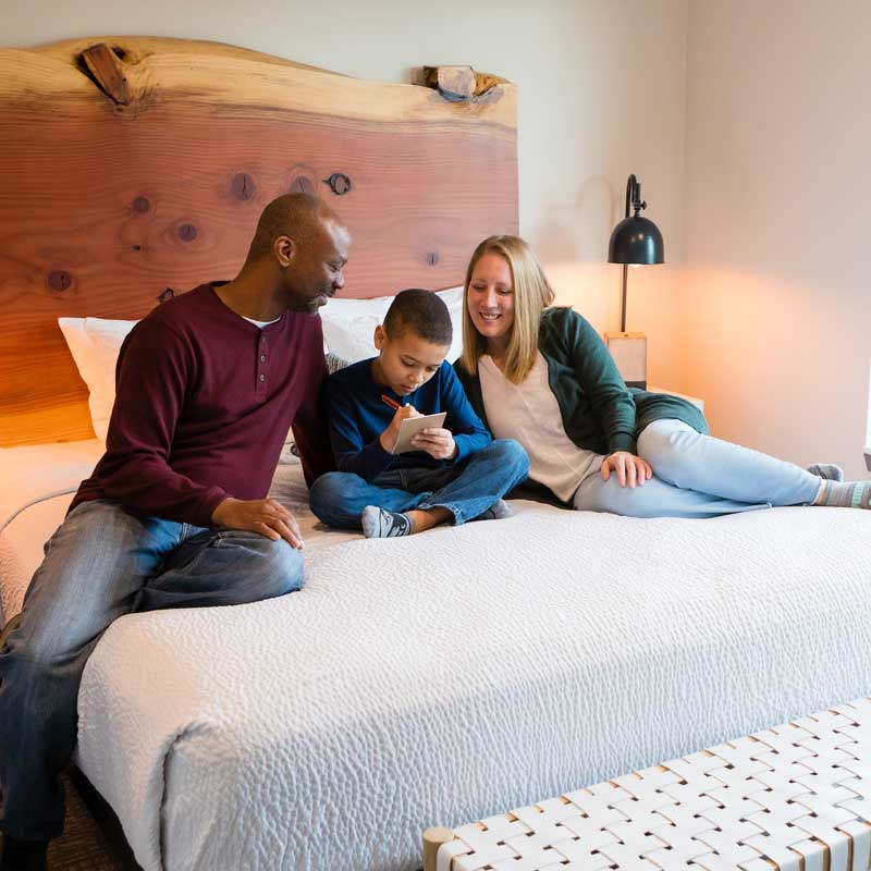 A family sits on a hotel bed.