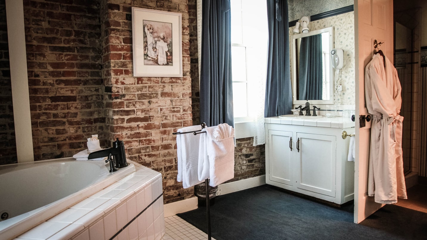 Porcelain bathroom fixtures are set in front of a brick wall and navy-blue accents.