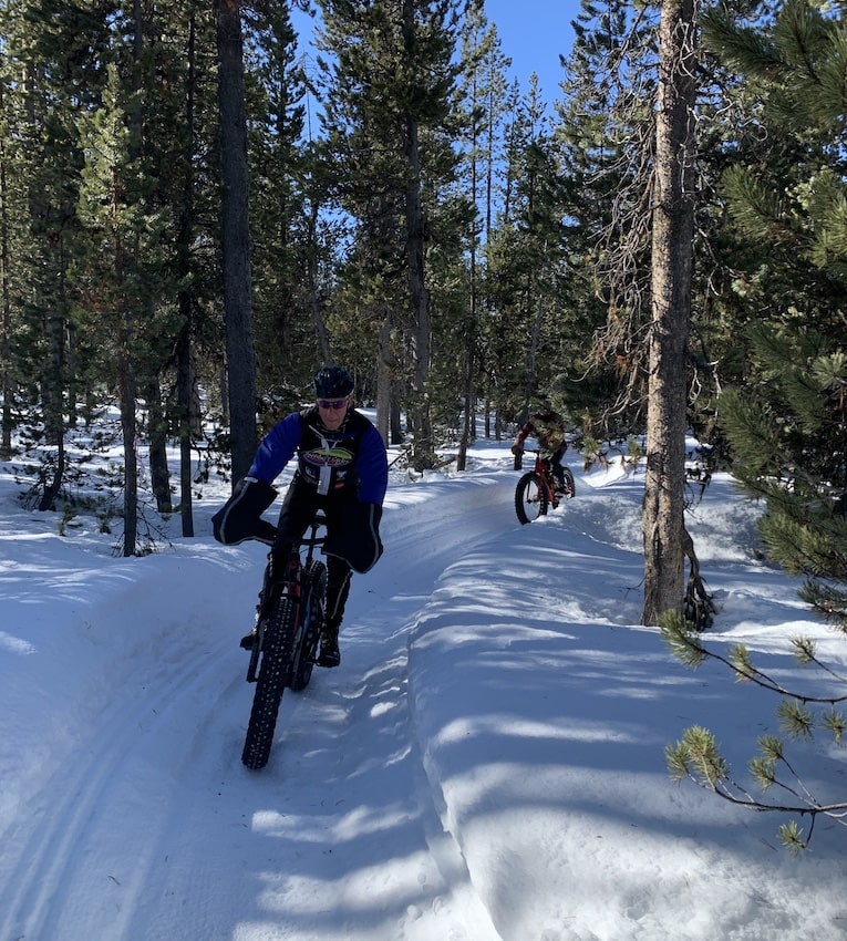 Bill bikes towards the camera between snow.