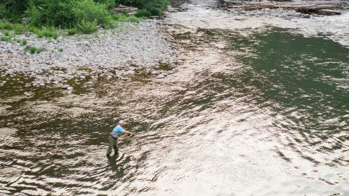 A lone fly fisherman in the middle of a river