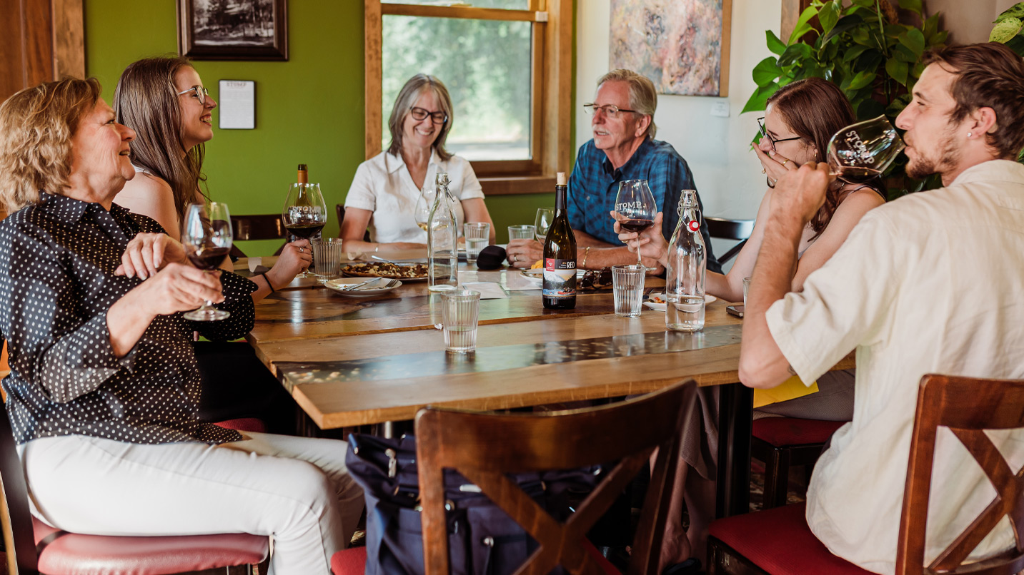 People sitting around a table drinking wine.