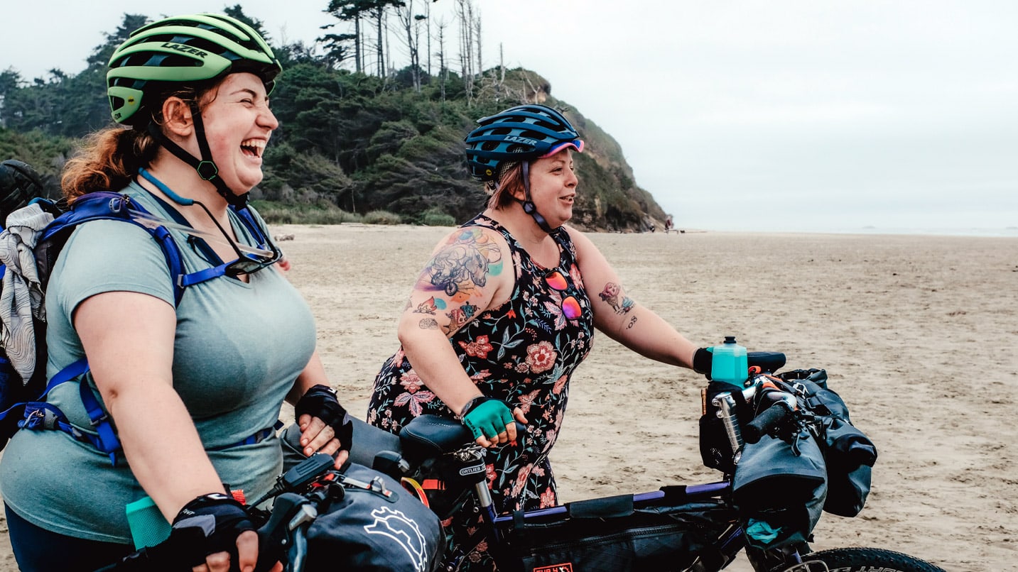 Two very happy women arrive at the beach with their bikes