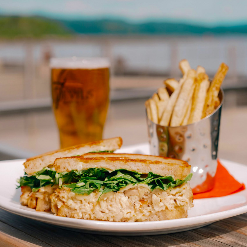 Food and beer on a waterfront outside table.