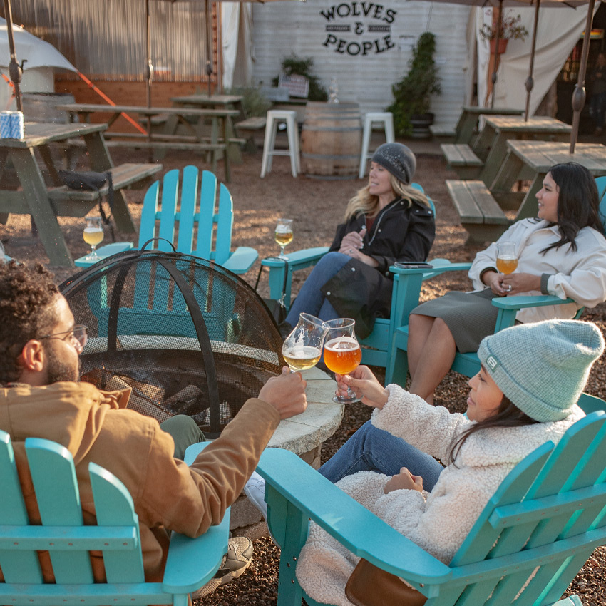 People drinking beer around an outdoor fire pit.