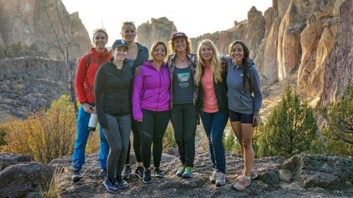 A group of women pose in front of towering rocks