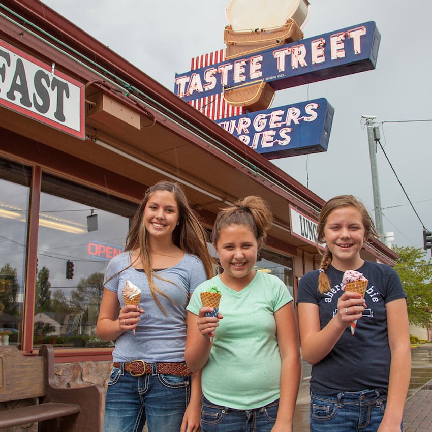 Three girls hold ice creams cones outside of an ice cream story