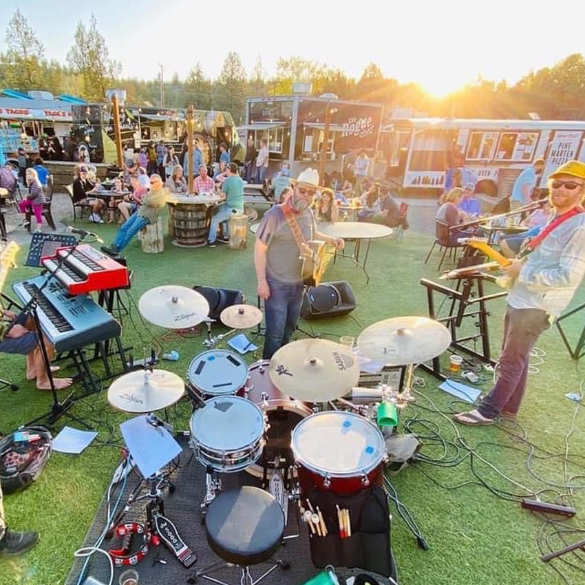 A band plays on a grassy field surrounded by food carts