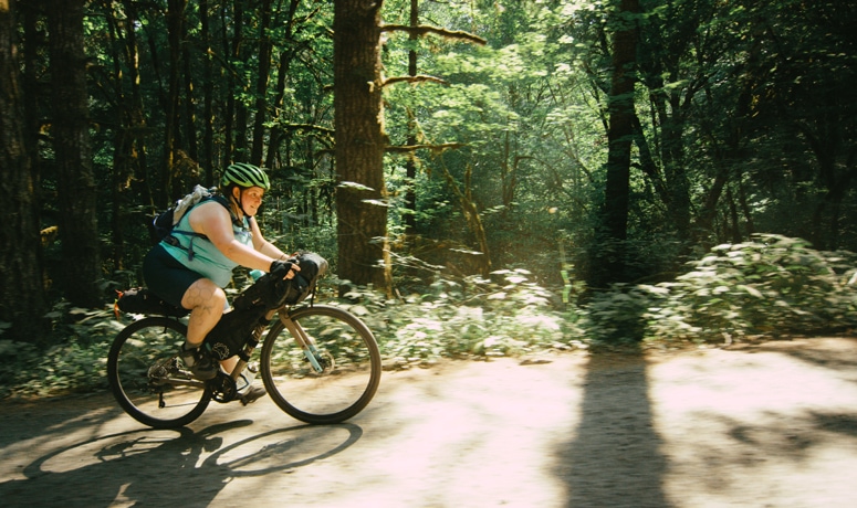 bicyclist riding gravel route in wooded landscape