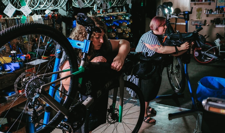 two bicyclists tuning up their bikes in a bike shop